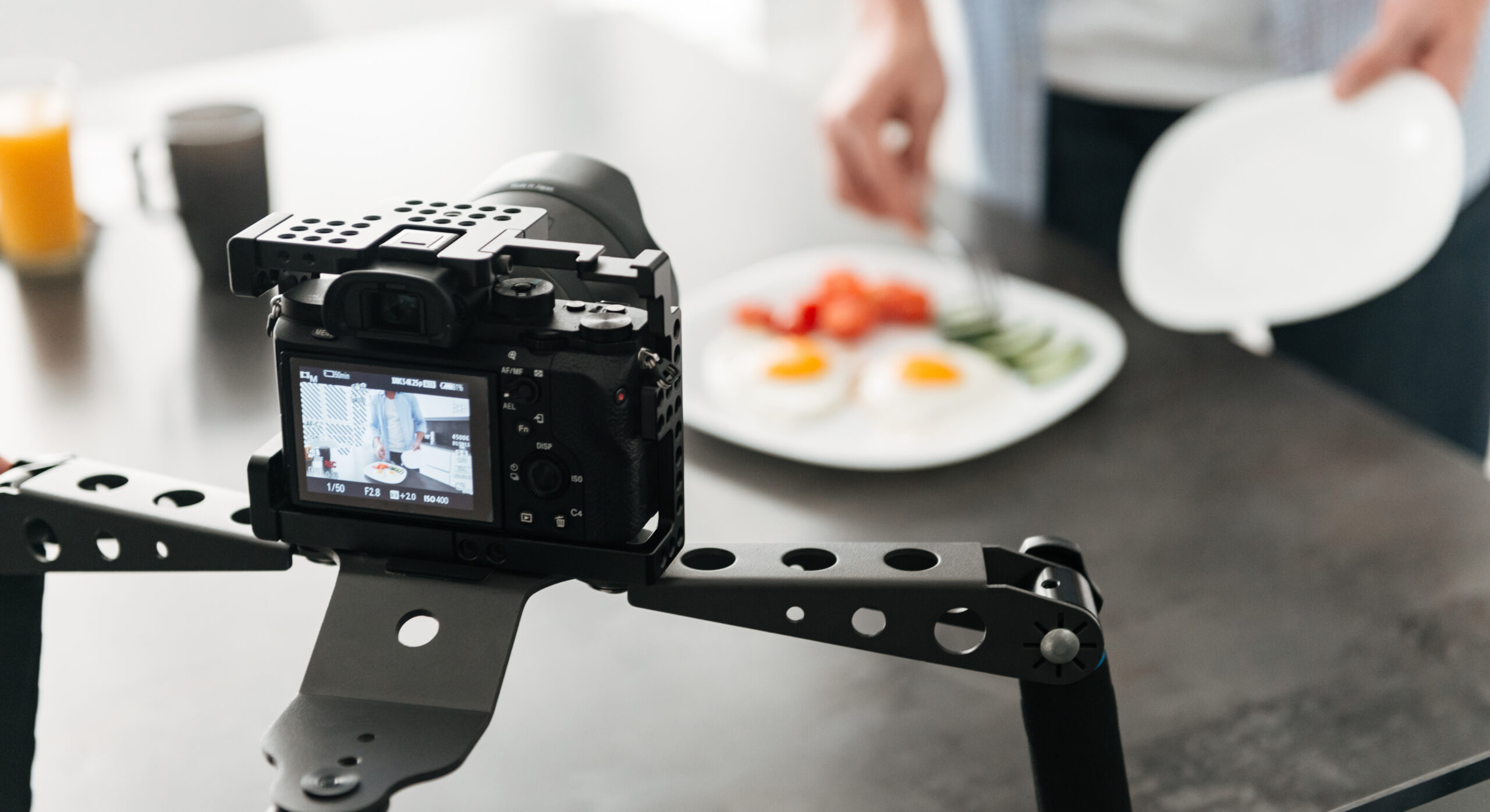 Man recording video food blog about cooking on dslr camera in kitchen at home