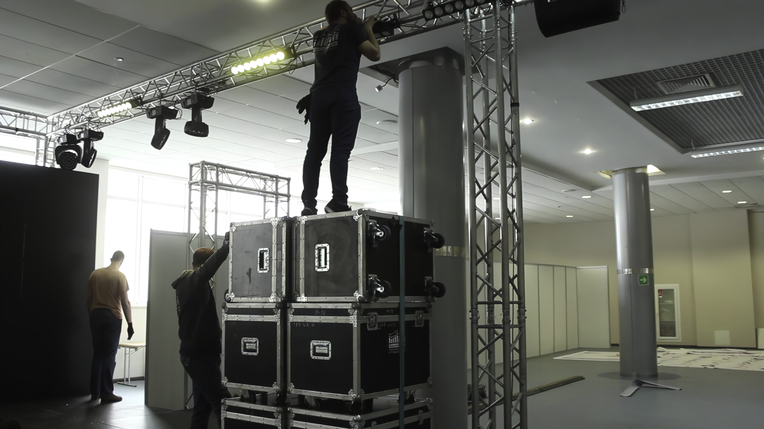 Technicians are setting up lighting and audio equipment for an exciting upcoming event in a spacious venue